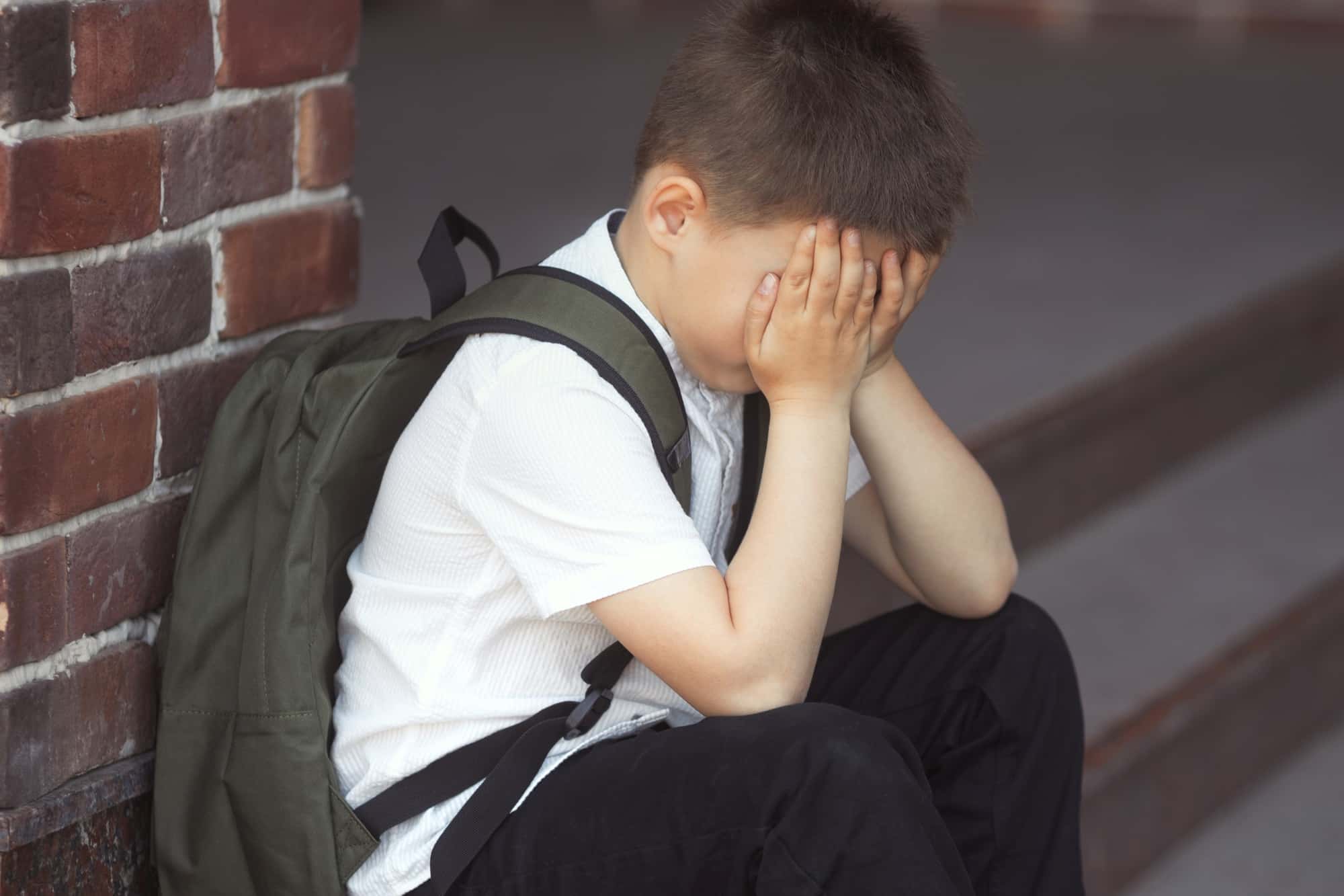 The child covered his face with his hands and cries.